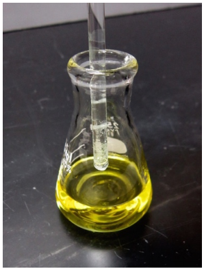 Figura 2: Una varilla de agitación de vidrio sumergida en una solución de benzil en etanol, para iniciar la cristalización.