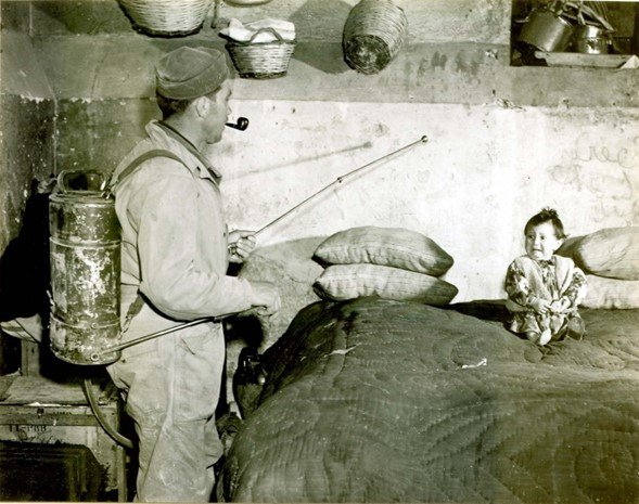 Soldado en una casa italiana rociando una mezcla de DDT y queroseno para controlar la malaria, 1945.
