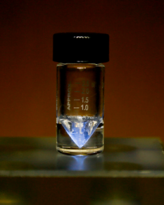 Radioisótopo médico actinio-225 en una v-vial en el ORNL. El resplandor azul procede de la ionización del aire circundante por partículas alfa. Oak Ridge National Laboratory
